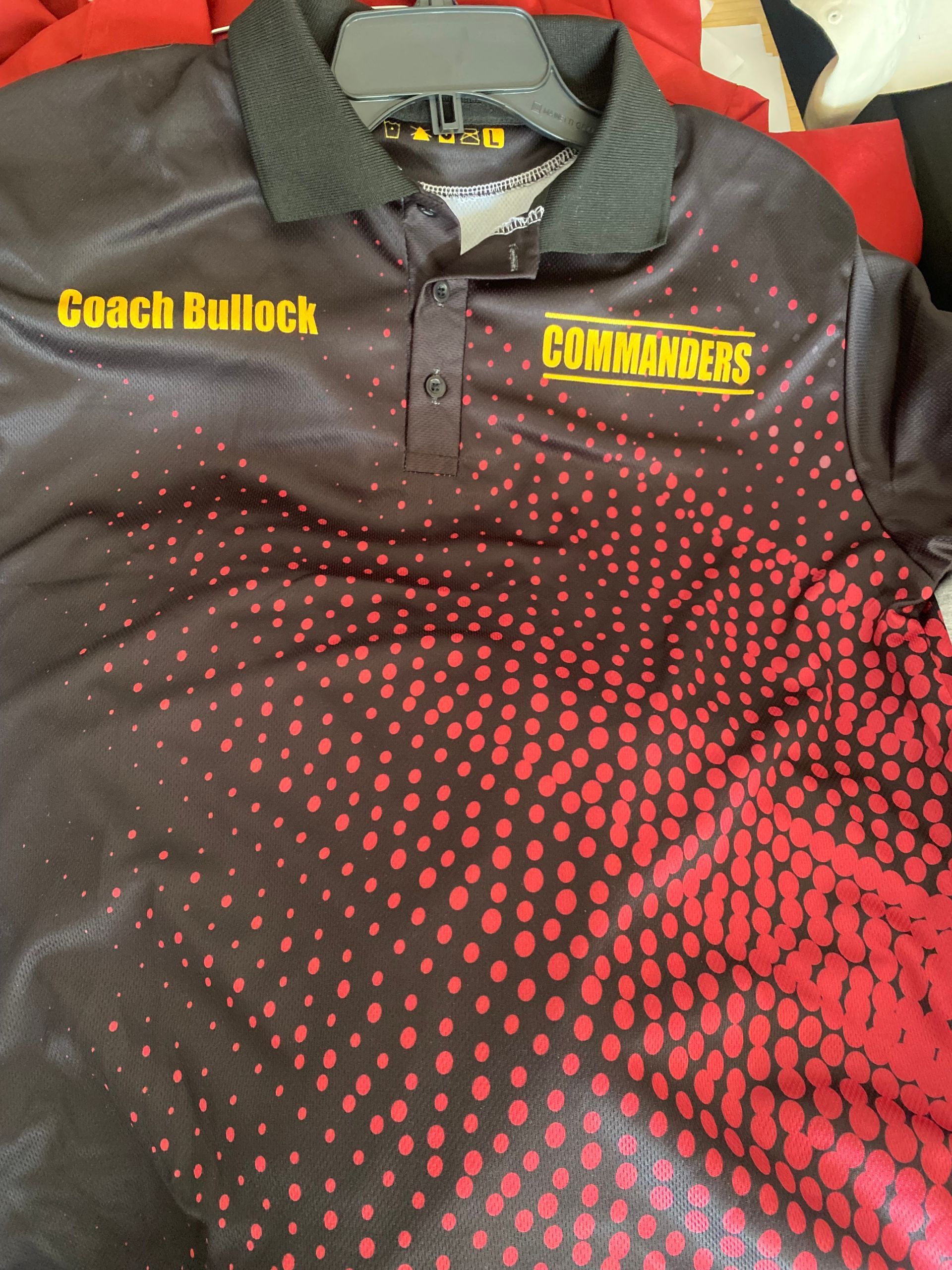 A black and red polo shirt with coach ballock written on it