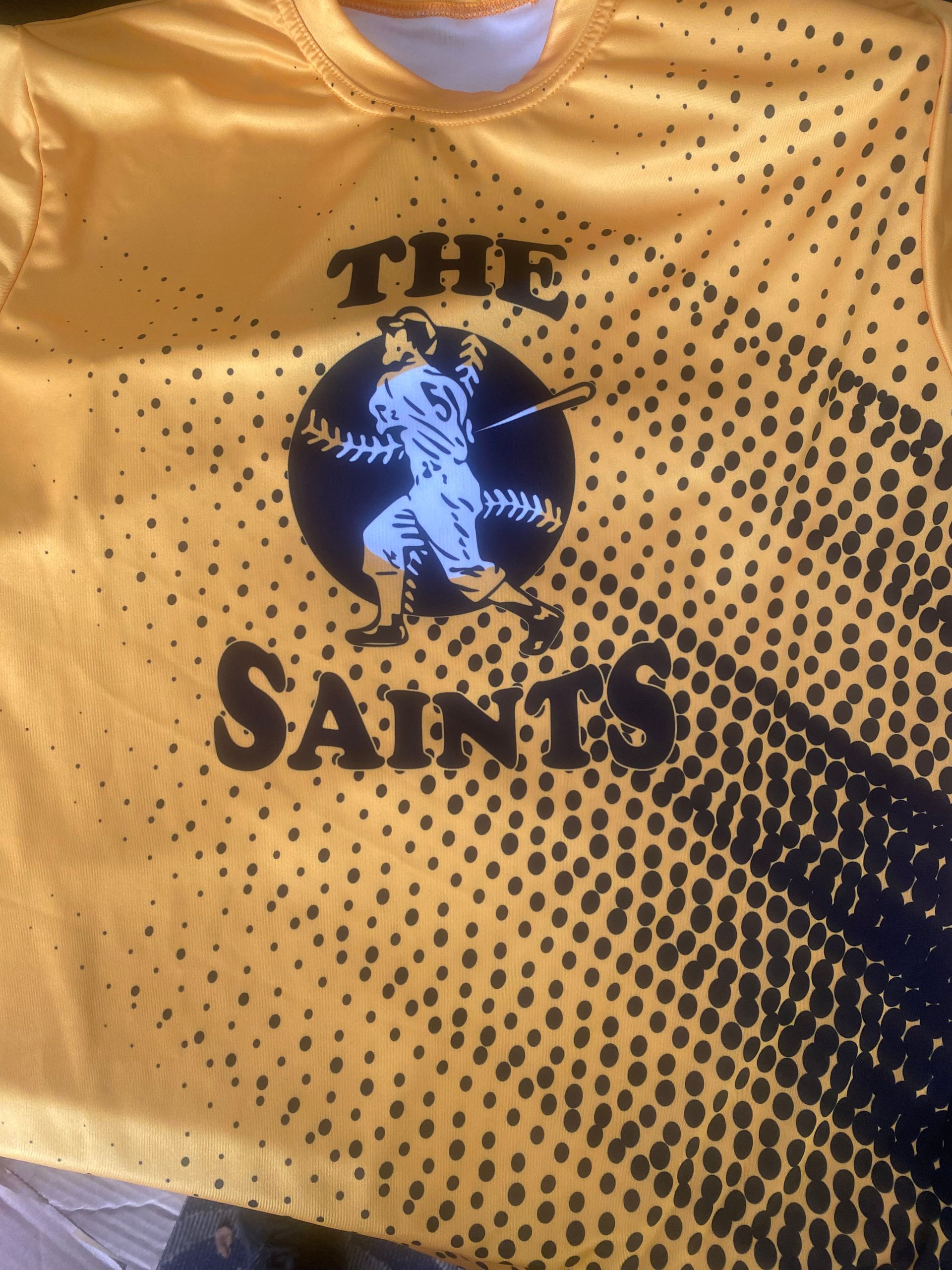 A yellow shirt that says the saints on it