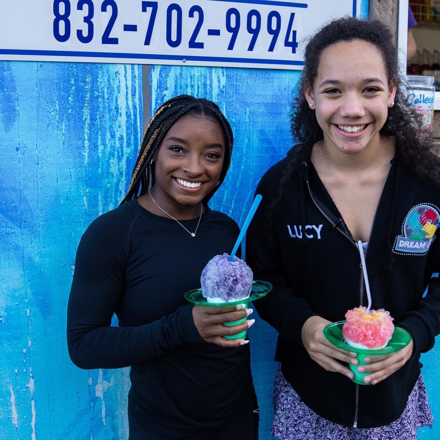 Two girls holding ice cream in front of a phone number