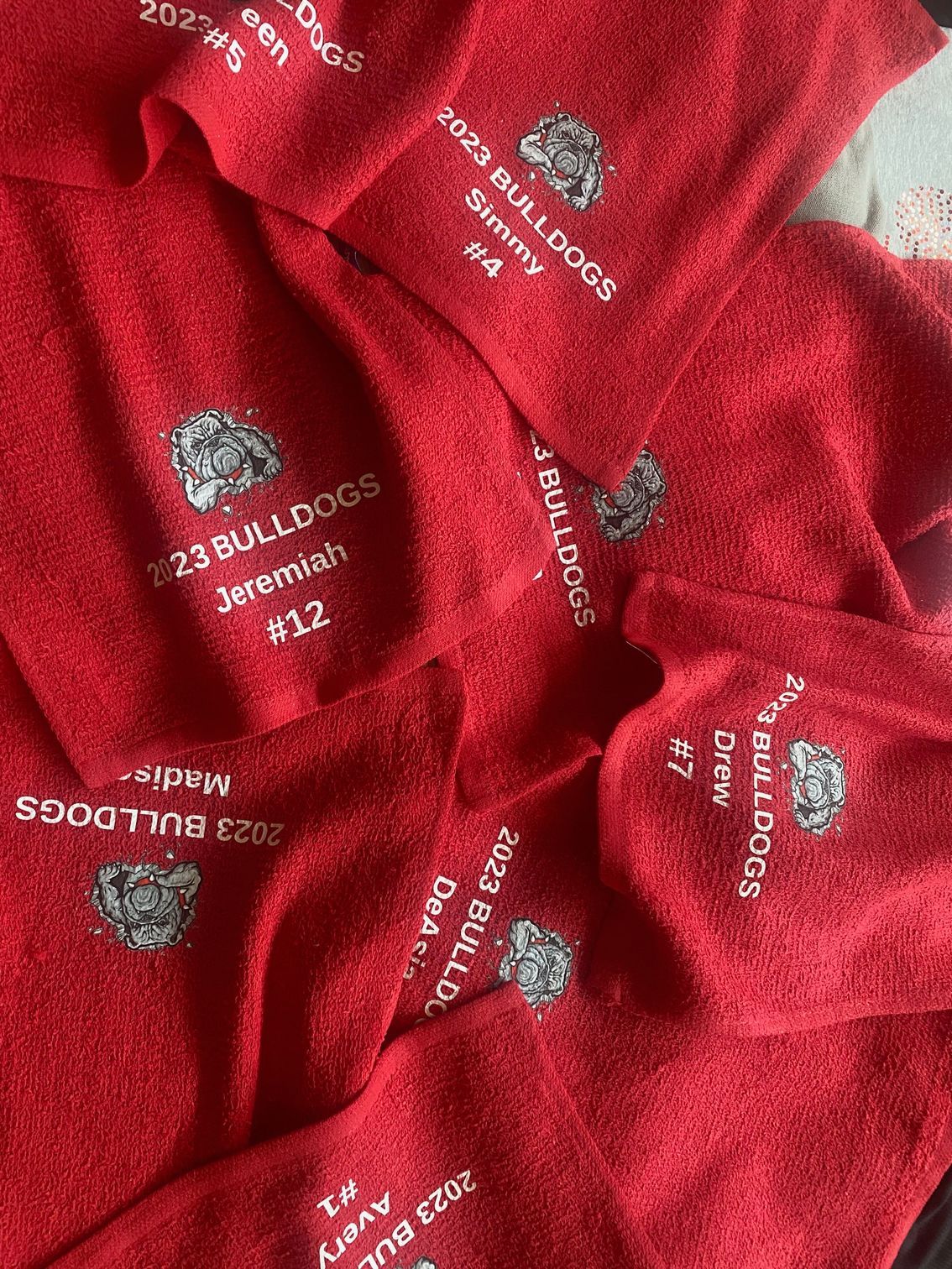 A pile of red towels with the word bulldogs embroidered on them.