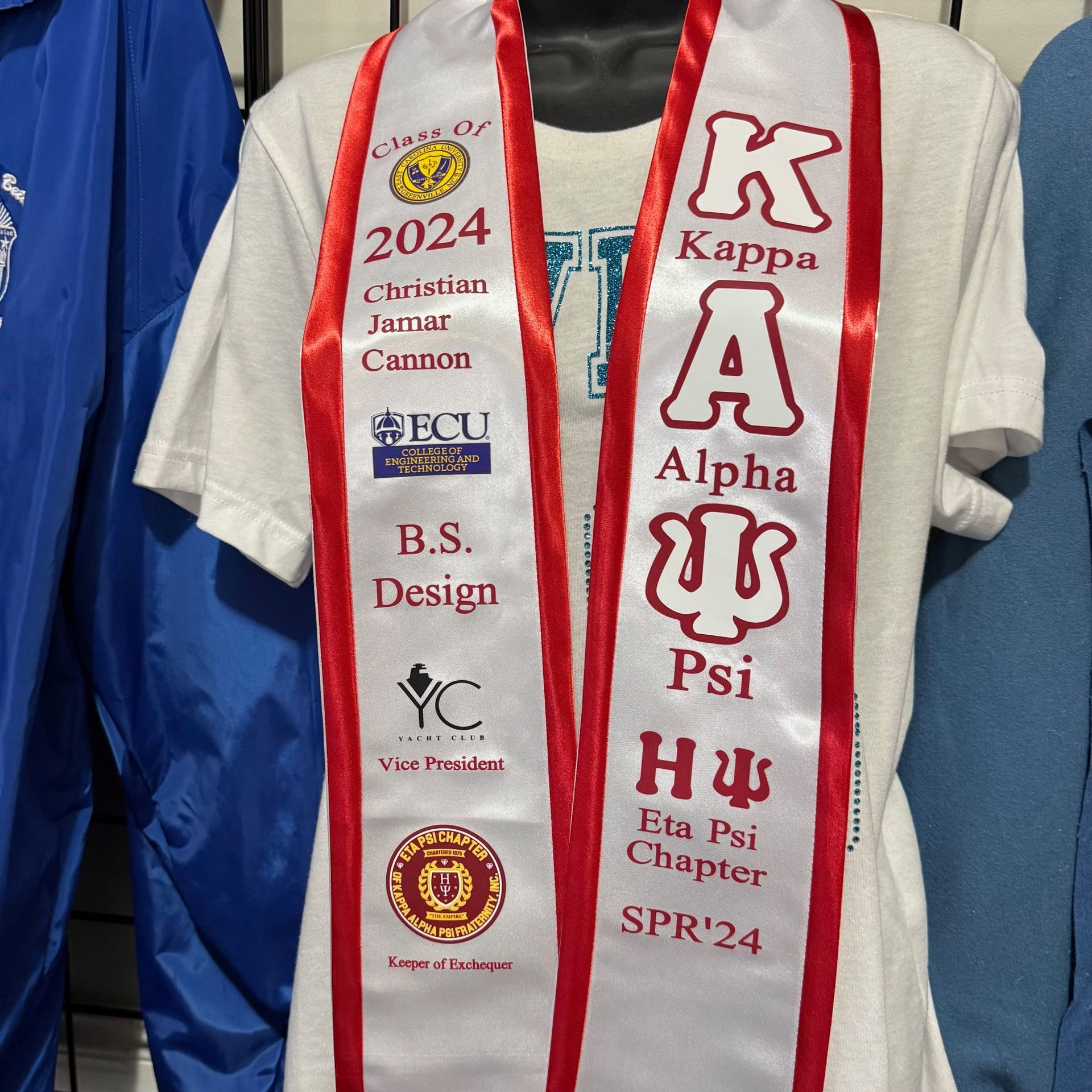 A white shirt with a red sash that says kappa alpha psi