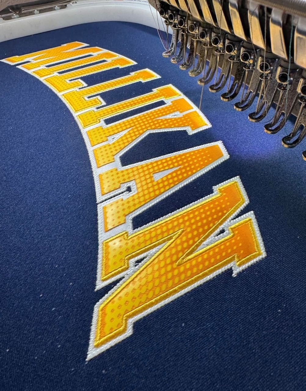 The word titans is being embroidered on a blue cloth