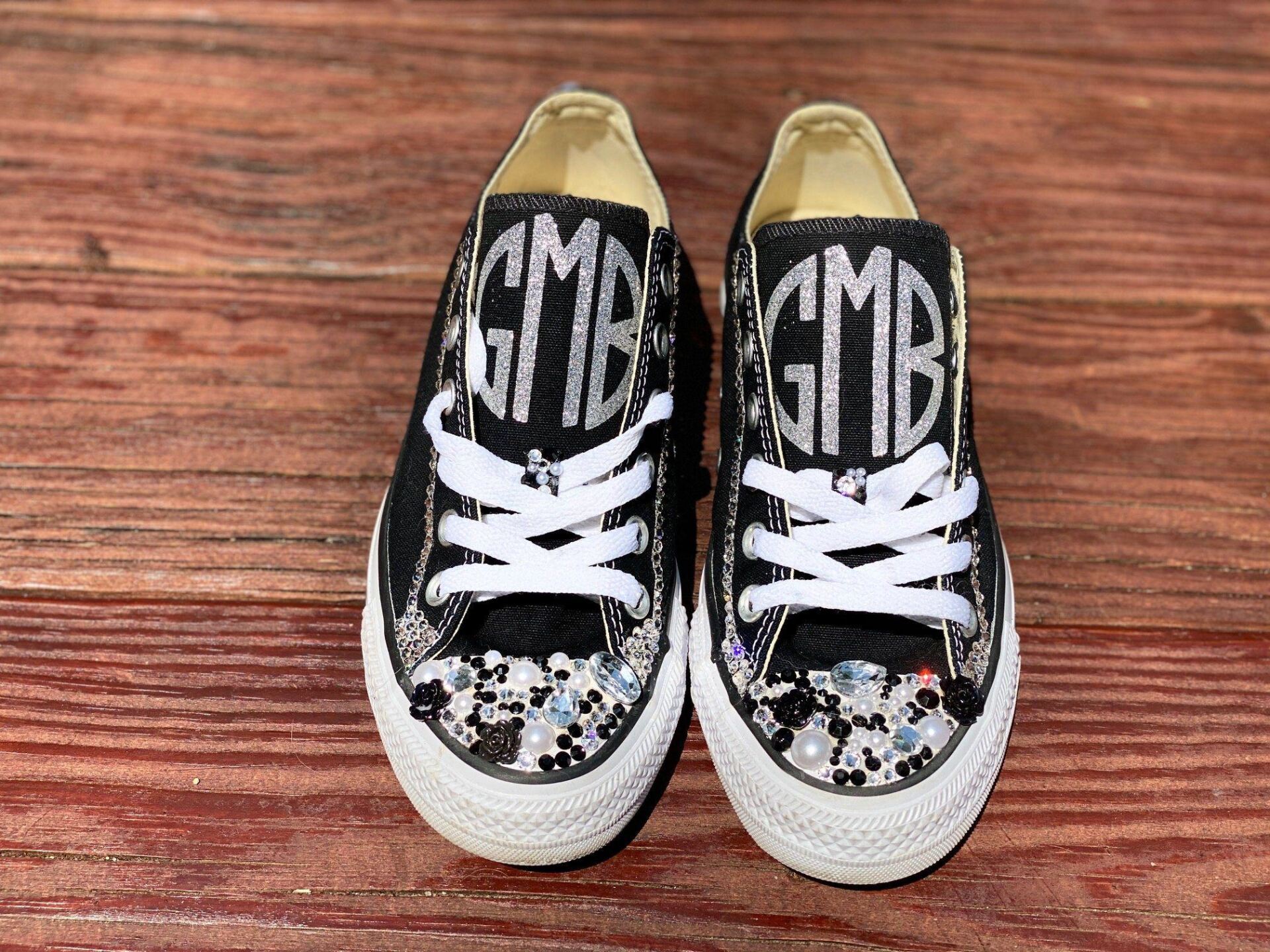 Pair of black Converse sneakers with white laces, glitter accents, and silver initials 