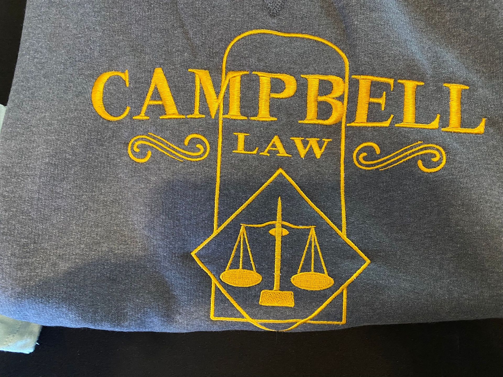 A gray shirt with campbell law embroidered on it