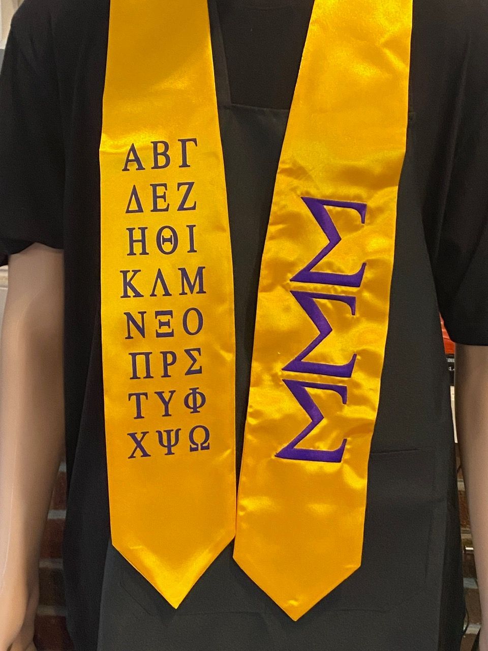 A person wearing a yellow sash with letters on it