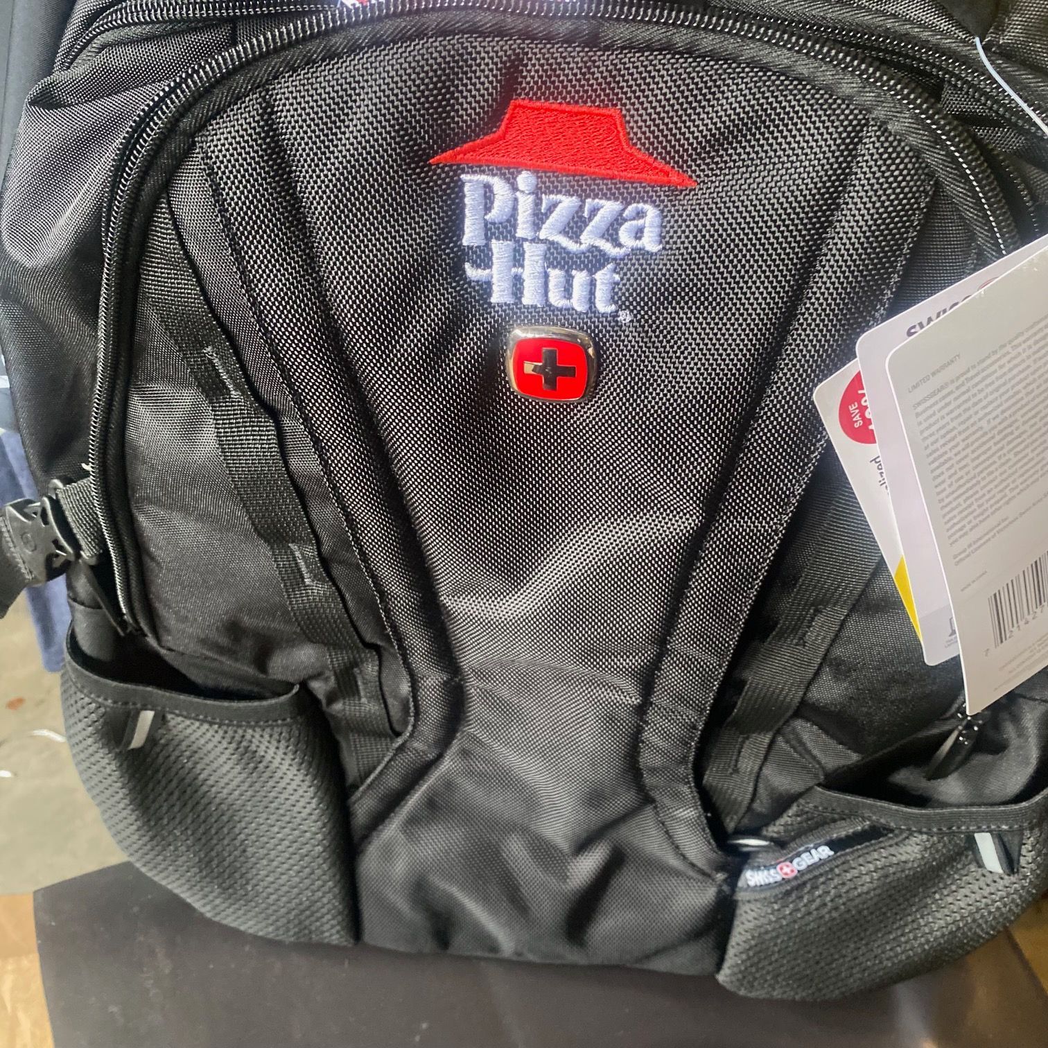 A pizza hut backpack is sitting on a wooden table.