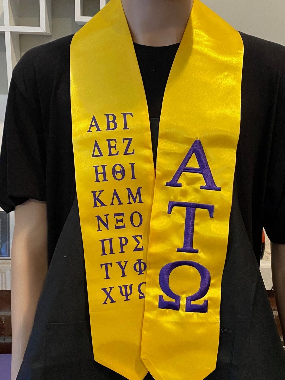 A person wearing a yellow sash with letters on it