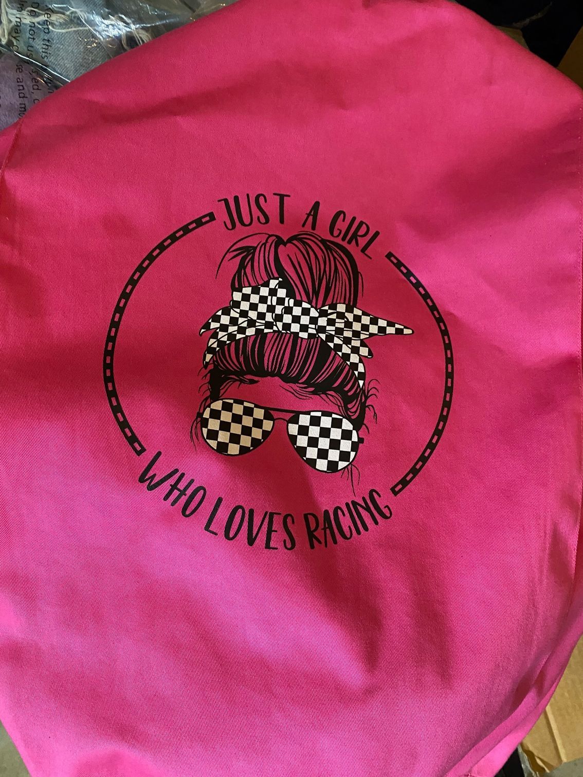 A pink shirt that says `` just a girl who loves racing ''