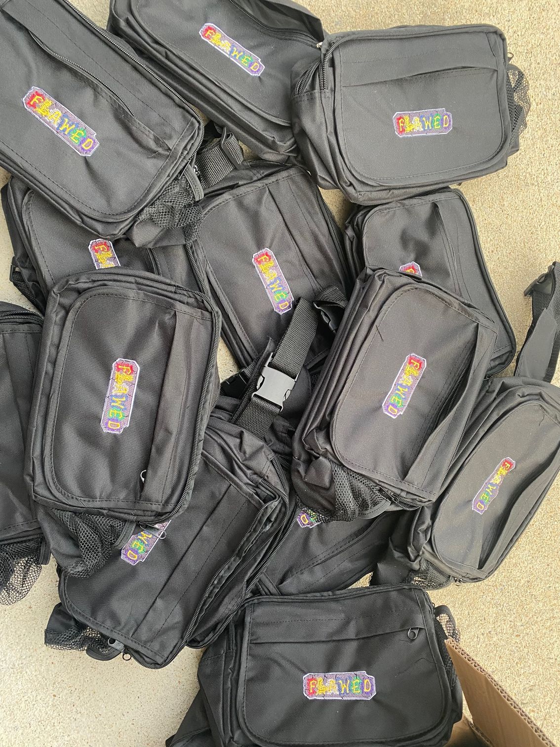 A bunch of black bags are sitting on top of each other on the floor.