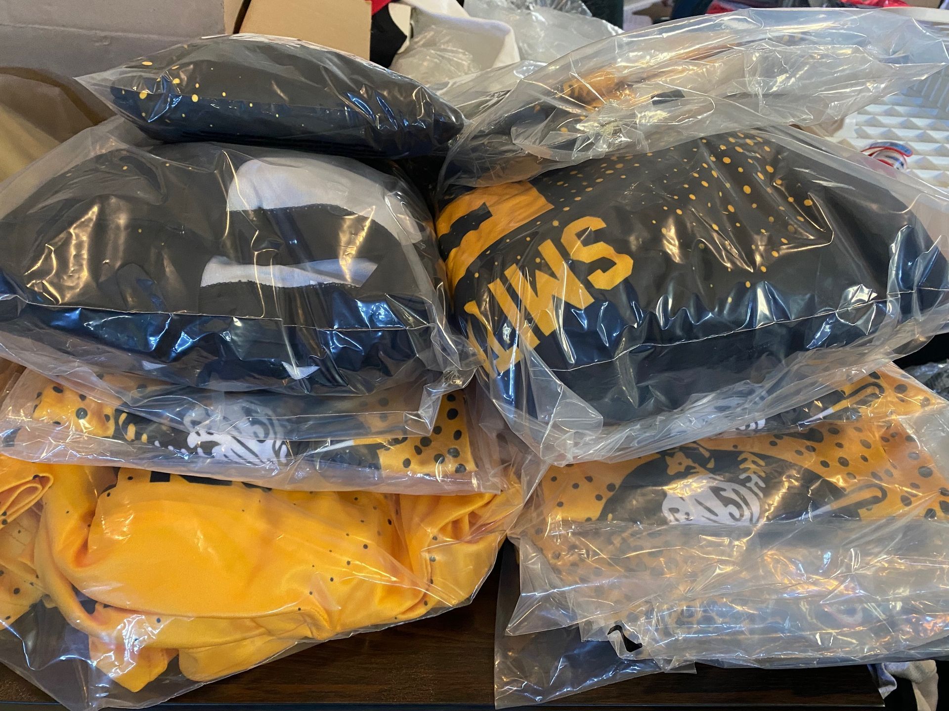 A bunch of bags of clothes are stacked on top of each other on a table.