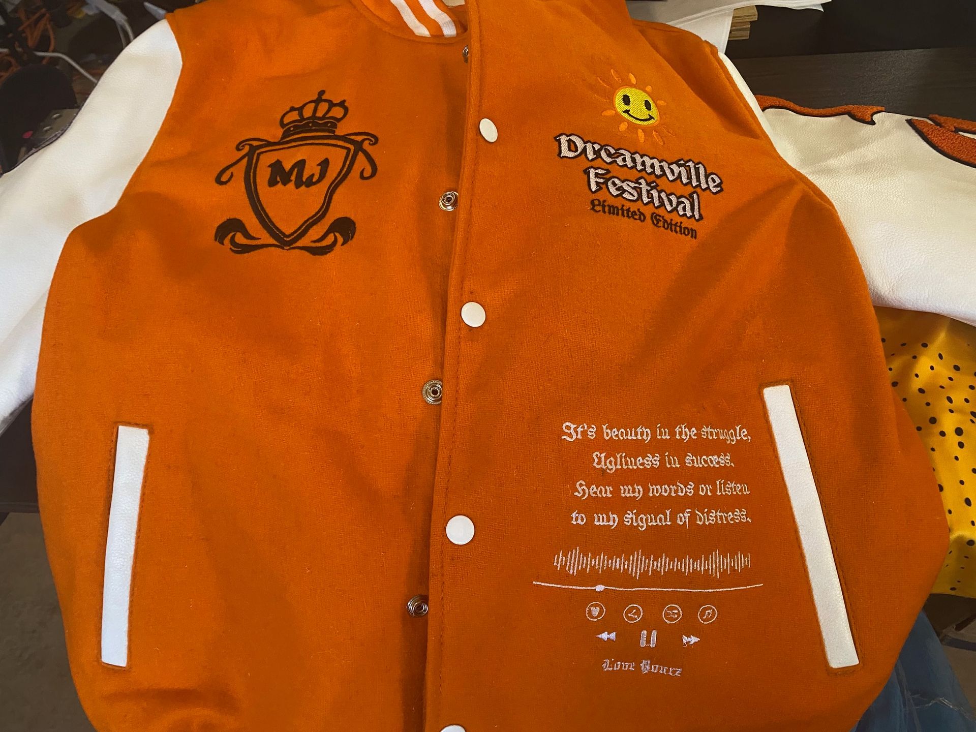 An orange and white varsity jacket that says dreamville festival