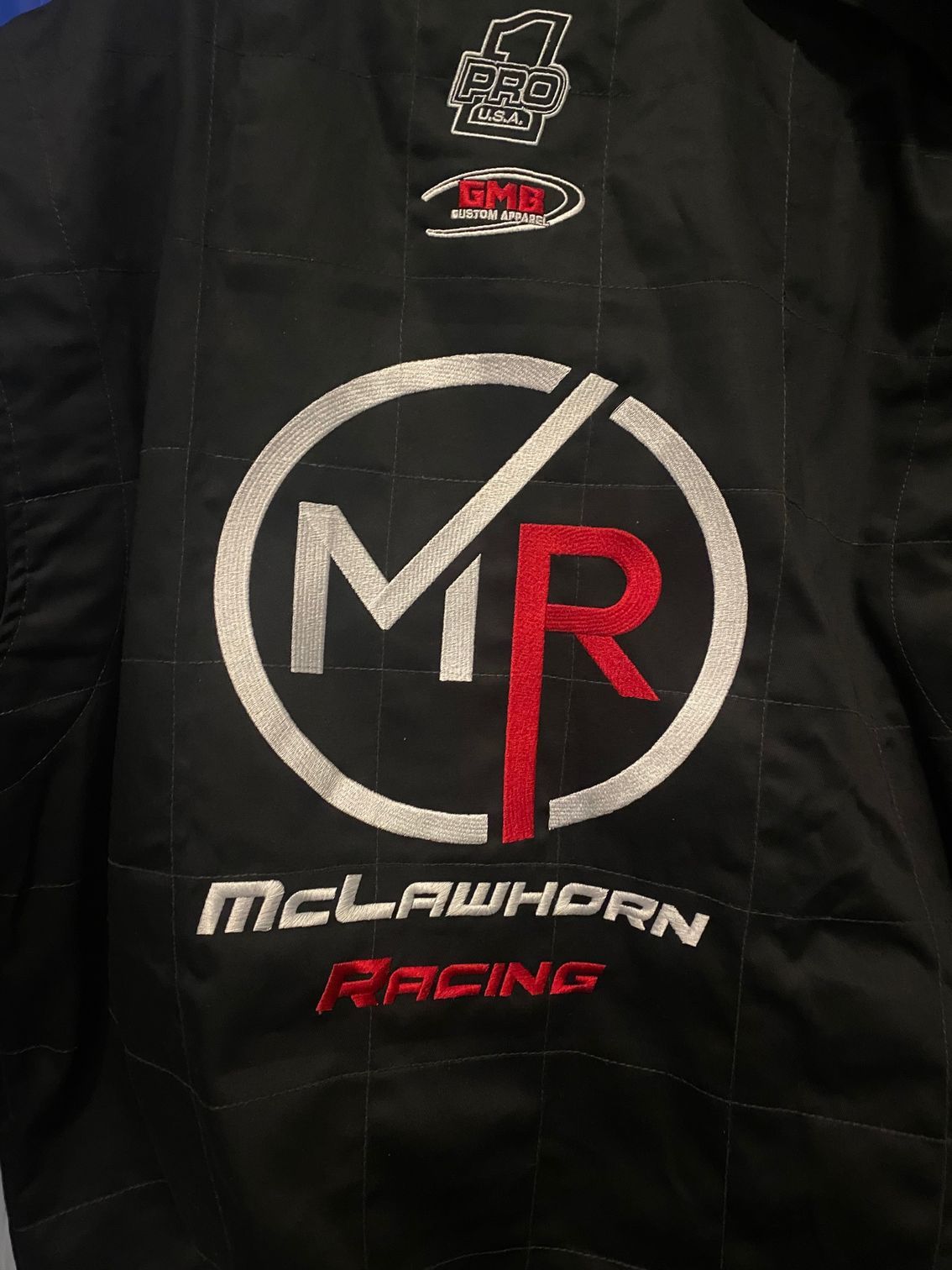 The back of a black jacket with a mclaren racing logo on it