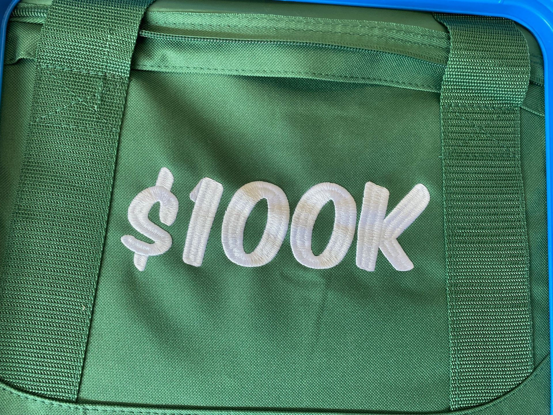 A green bag that says $ 100k on it