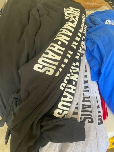 A pile of shirts including one that says ' usman-haus ' on it