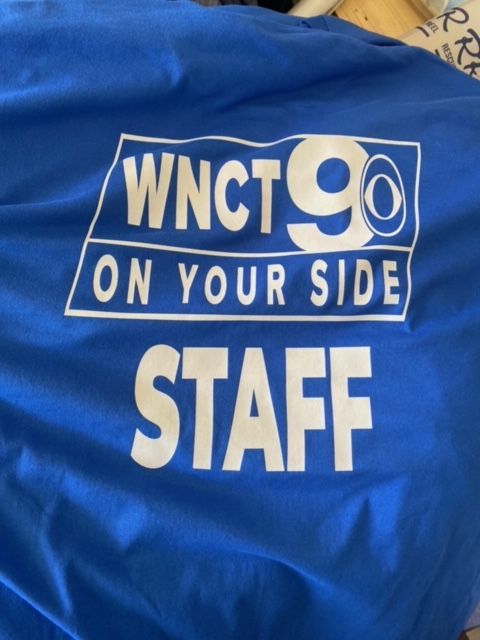 A blue shirt says wnct 90 on your side staff