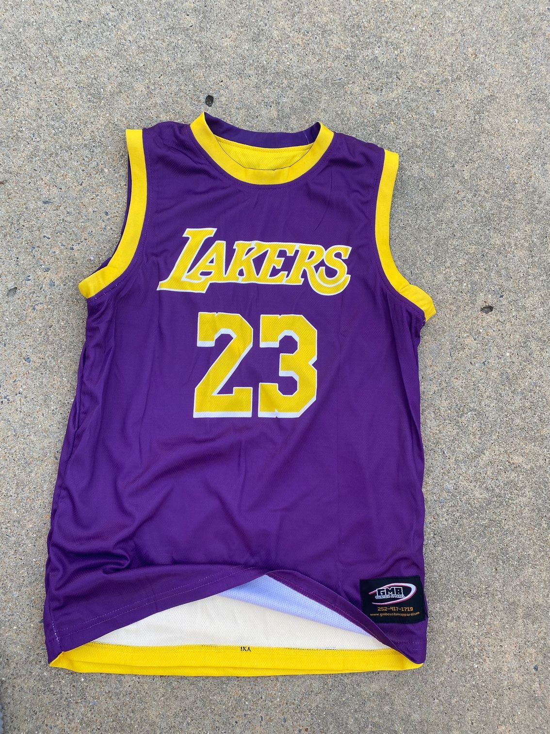A purple and yellow lakers jersey is sitting on the ground.