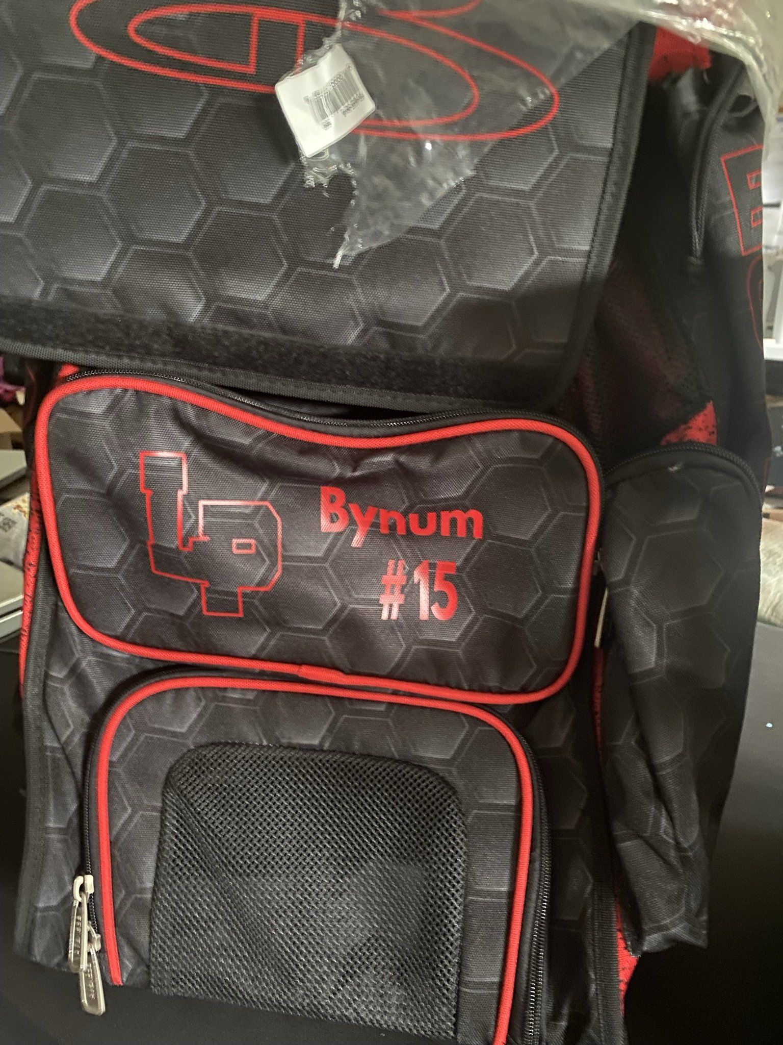A black and red backpack with the number 15 on it is sitting on a table.