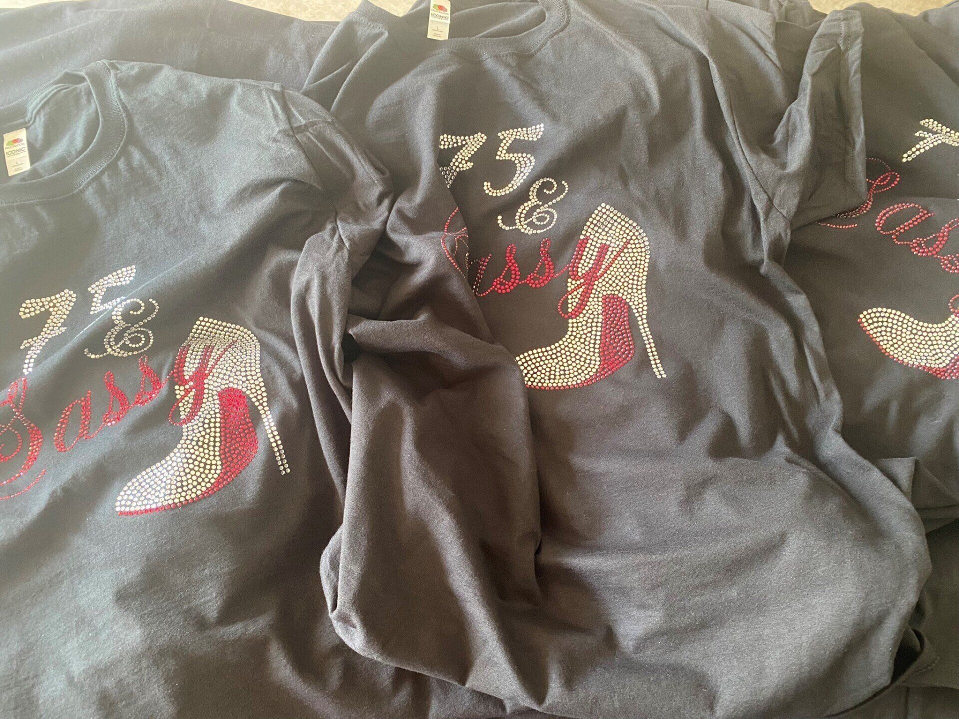 Three t-shirts with high heels on them are stacked on top of each other.