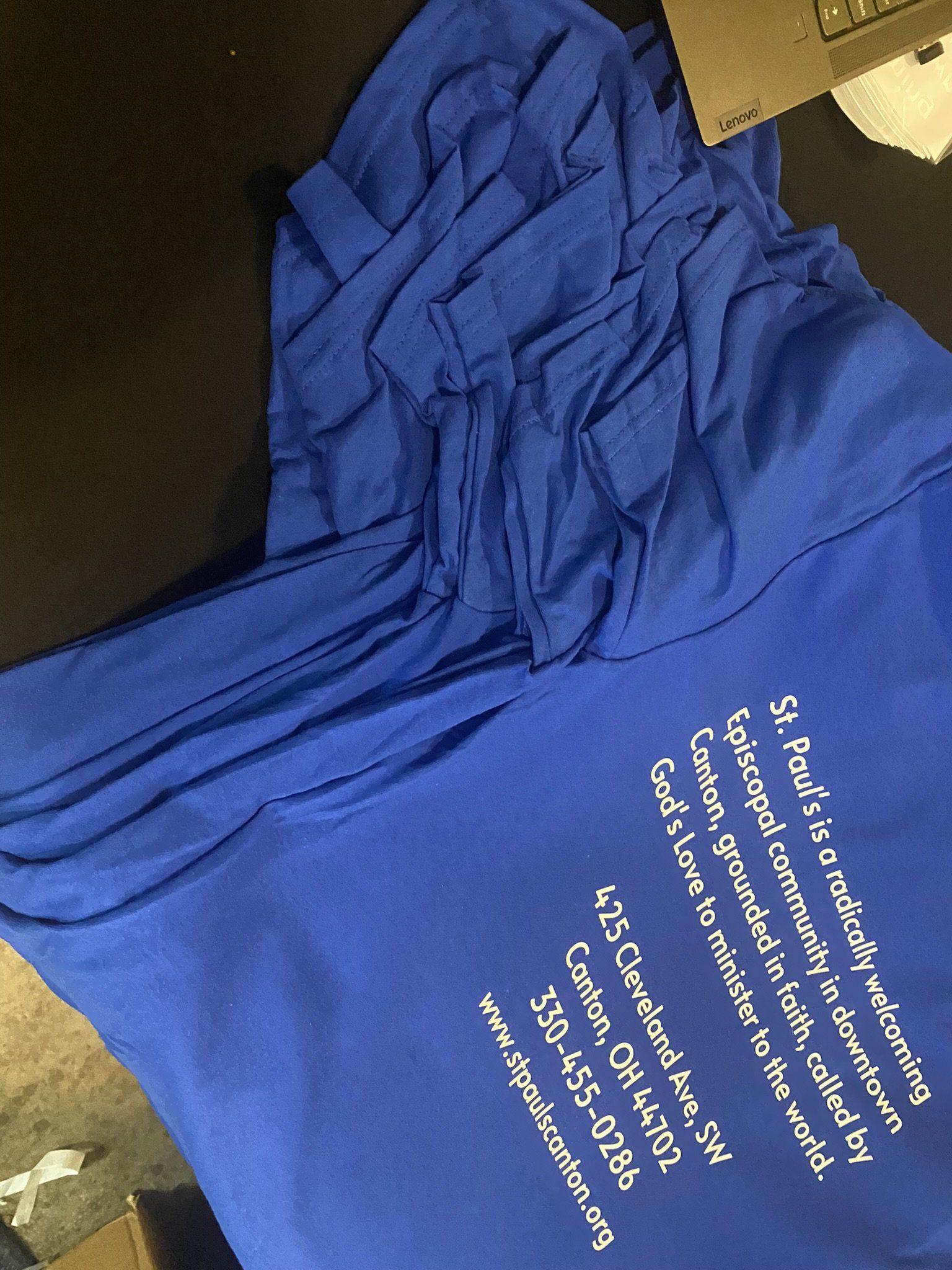 A pile of blue t-shirts with white writing on them