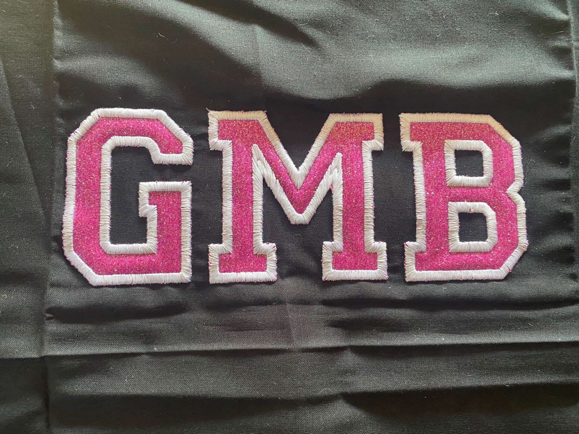 The word gmb is embroidered on a black shirt