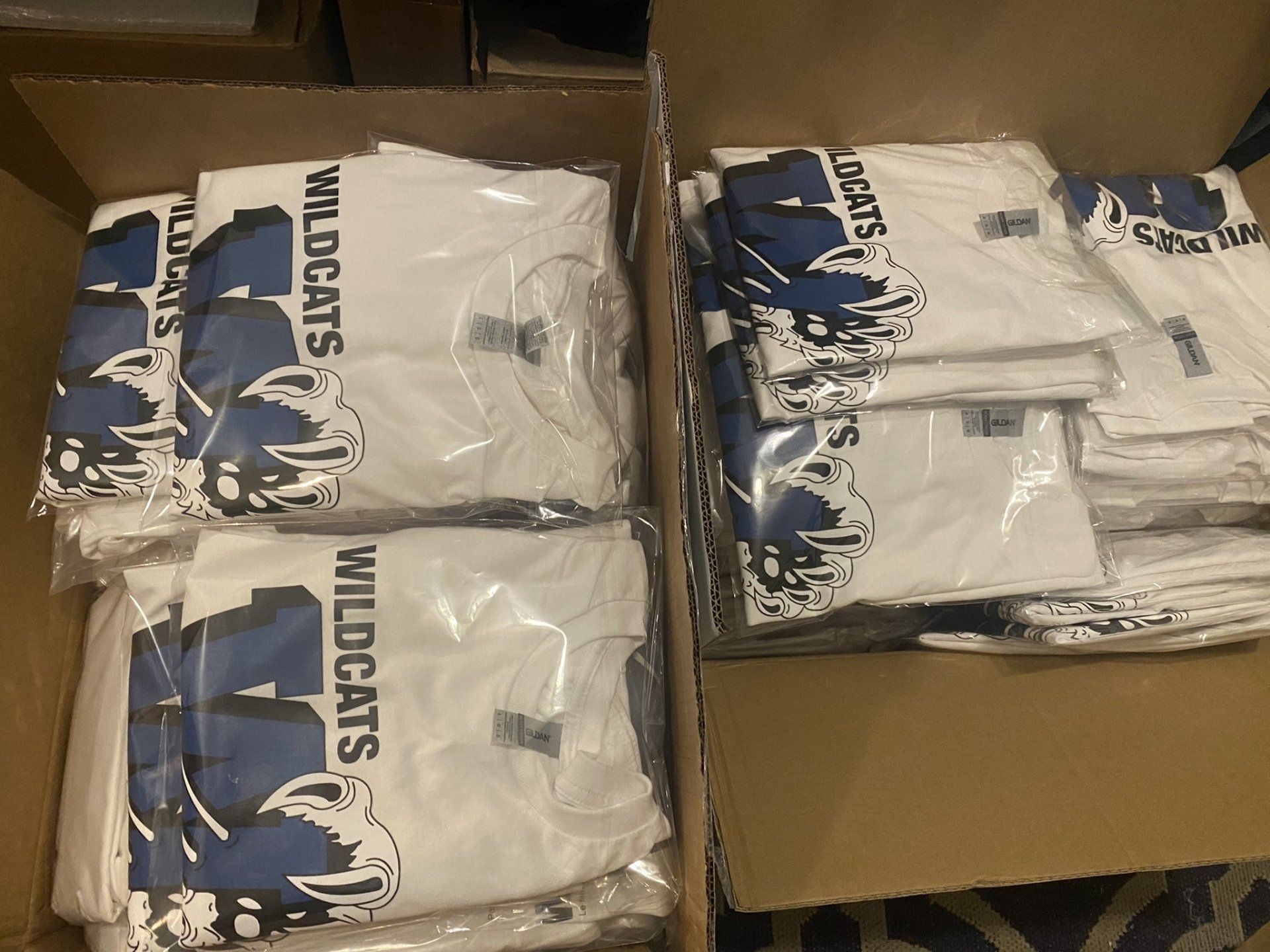 A box of wildcats t-shirts in plastic bags
