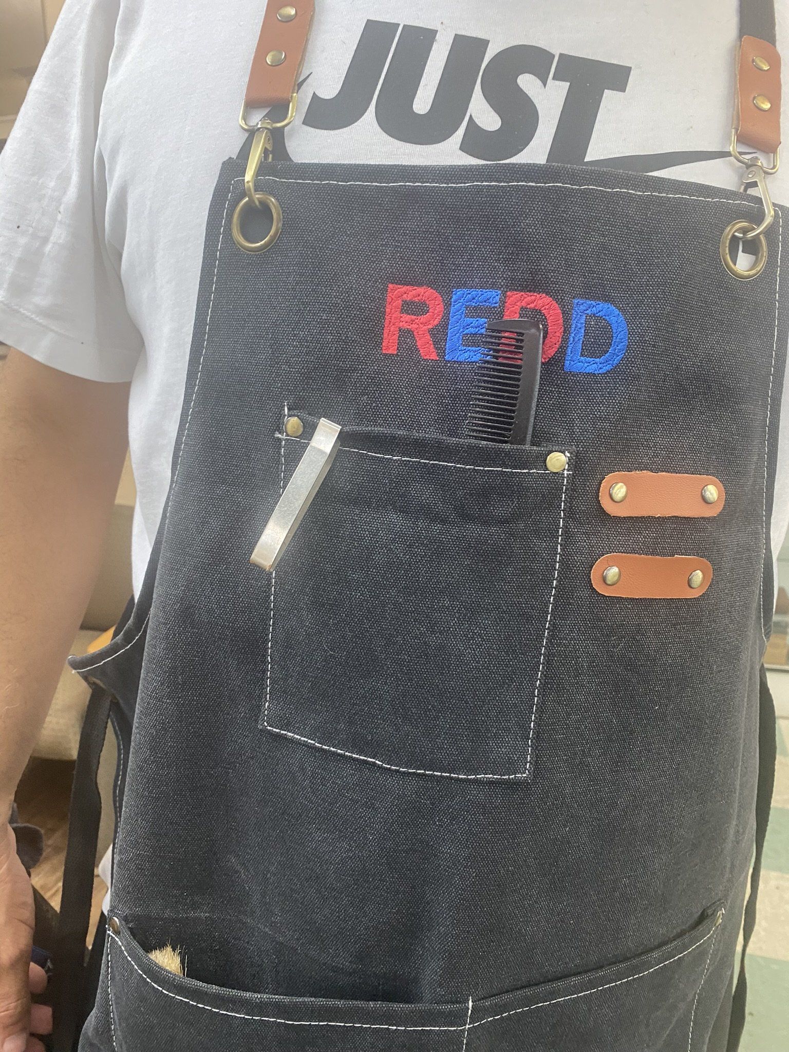 A person wearing a black apron with the word red on it.