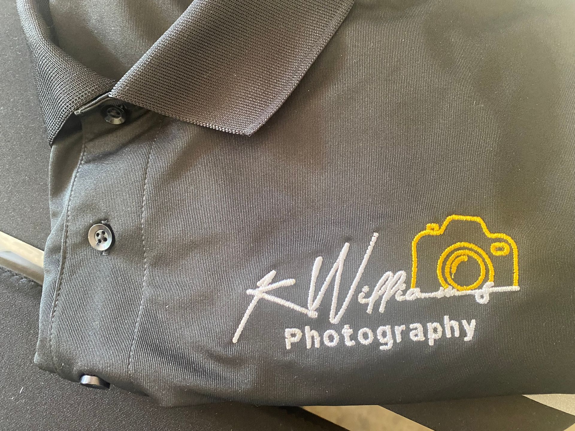 A black polo shirt with the word photography embroidered on it