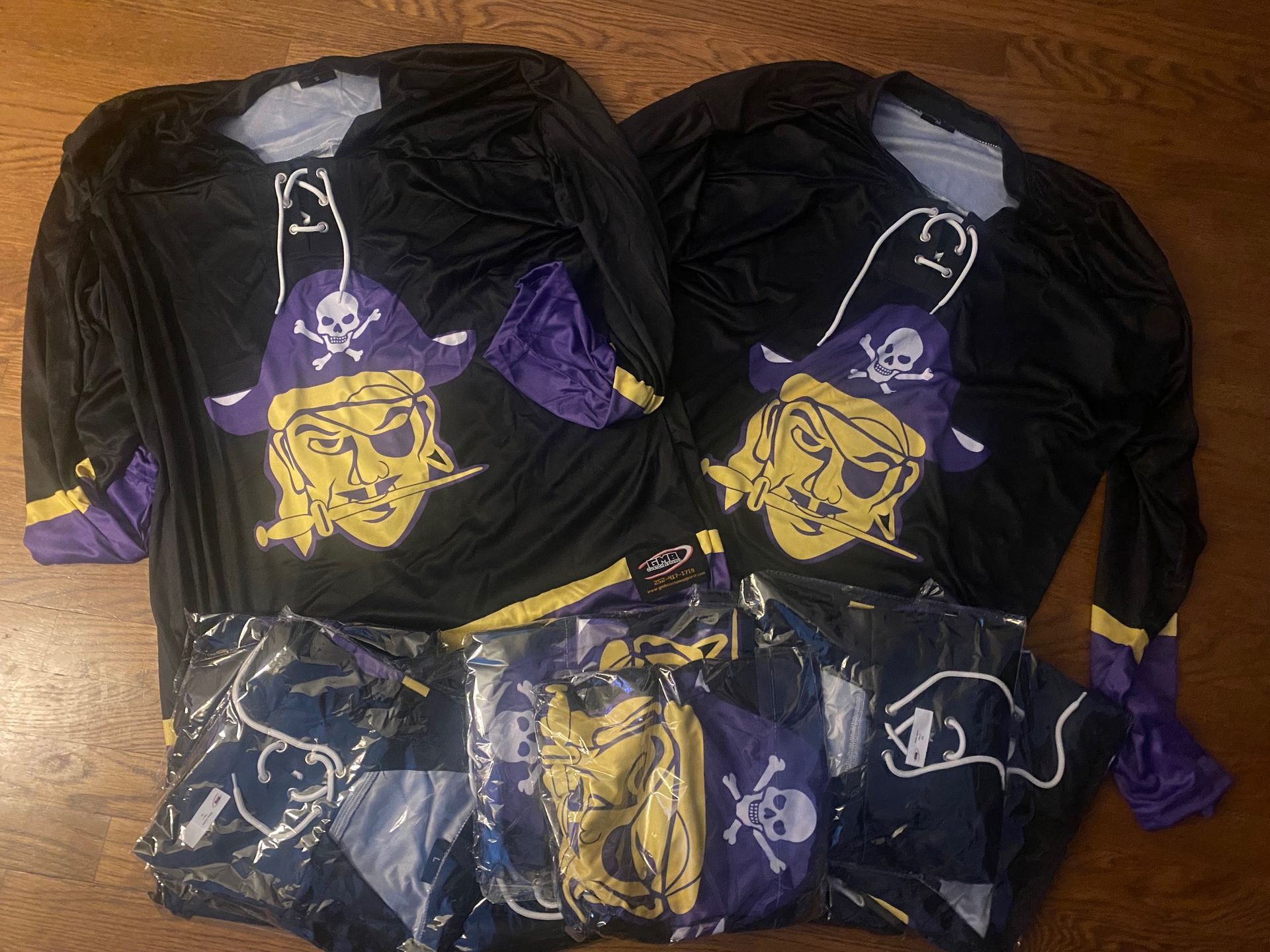 A bunch of pirate shirts are laying on a wooden table
