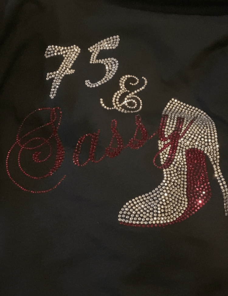 A black shirt with rhinestones on it says 75 & sassy