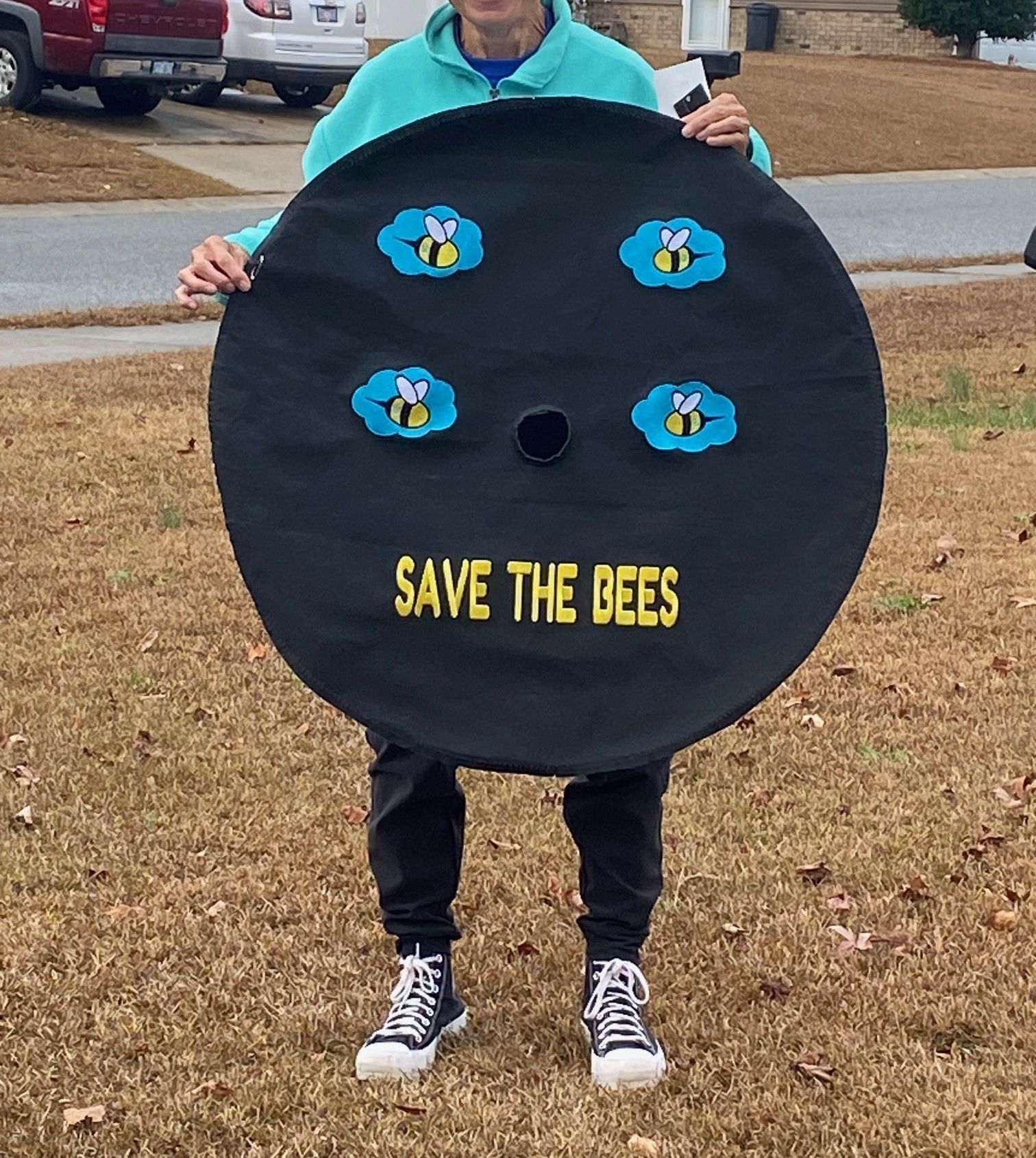 A person holding a tire cover that says save the bees