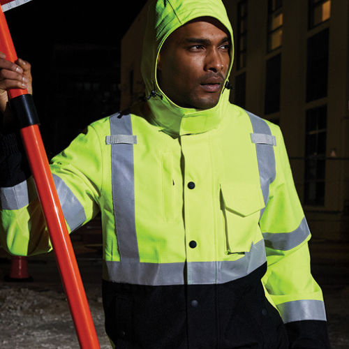 A man in a yellow and black jacket is holding an orange pole