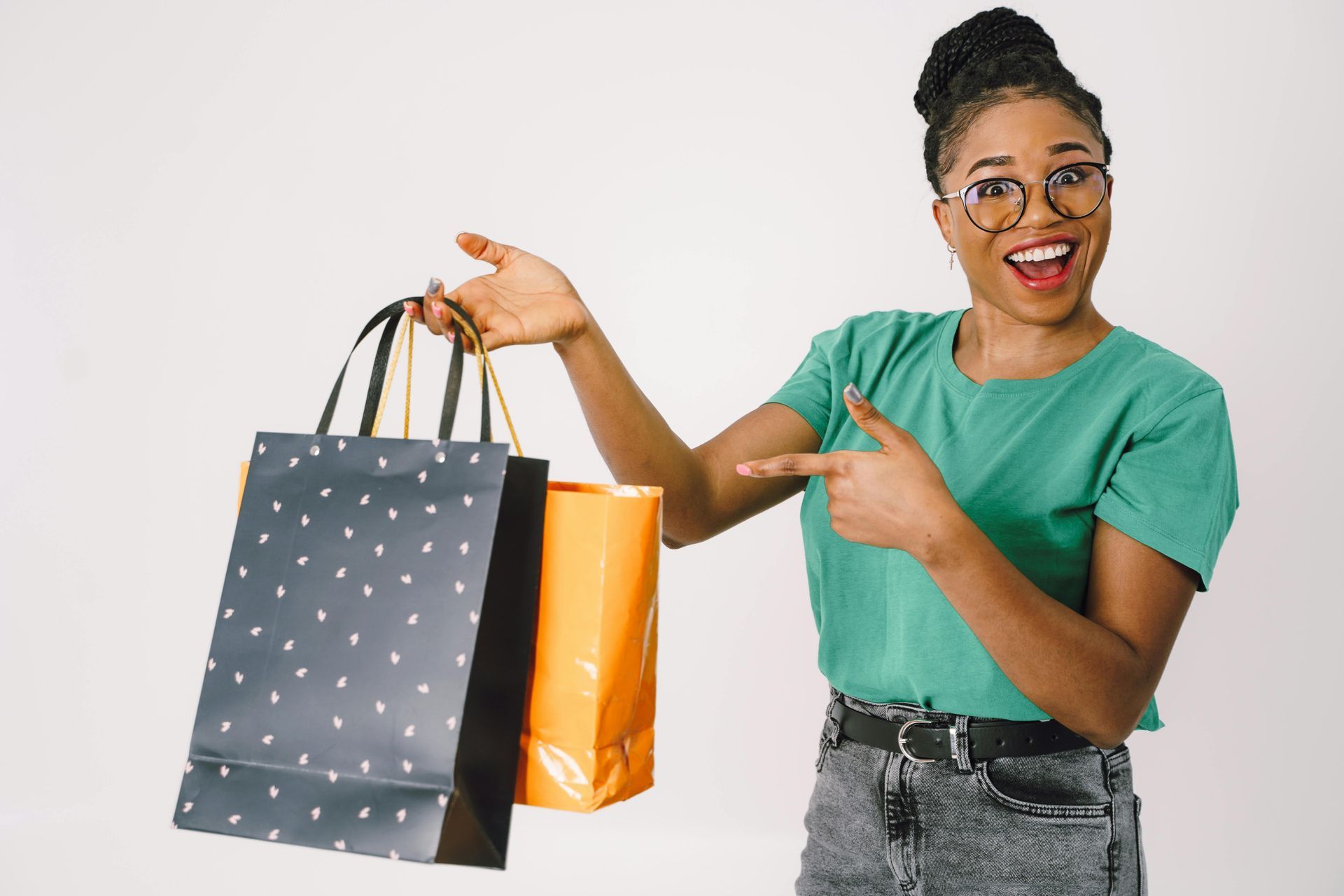 A woman is holding two shopping bags and pointing at them.