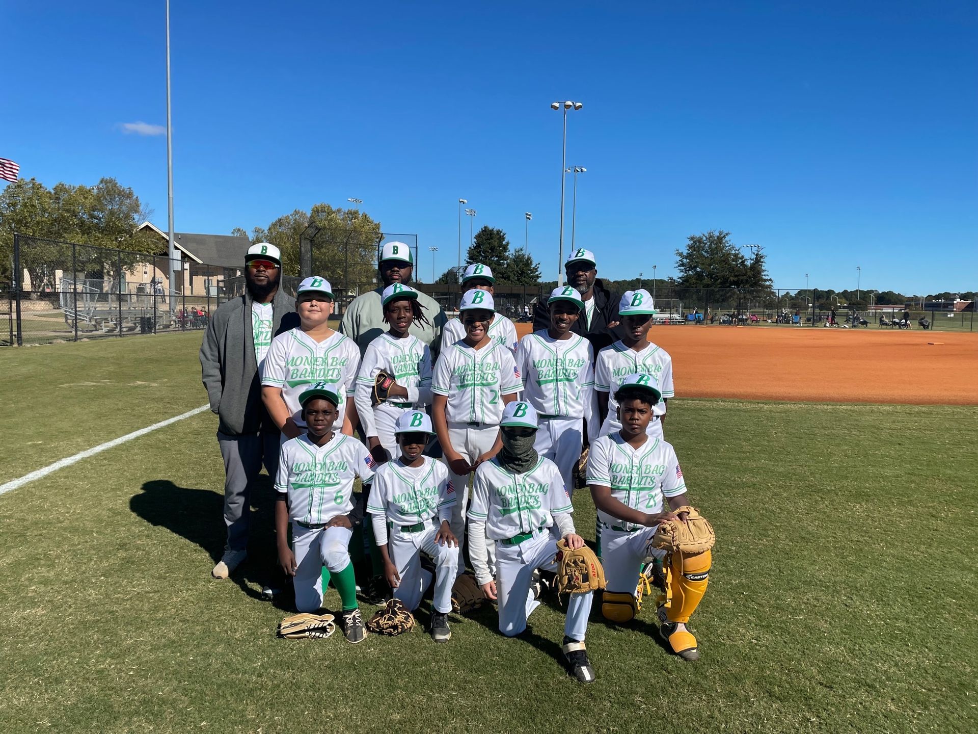 A group of young boys are posing for a picture on a baseball field.