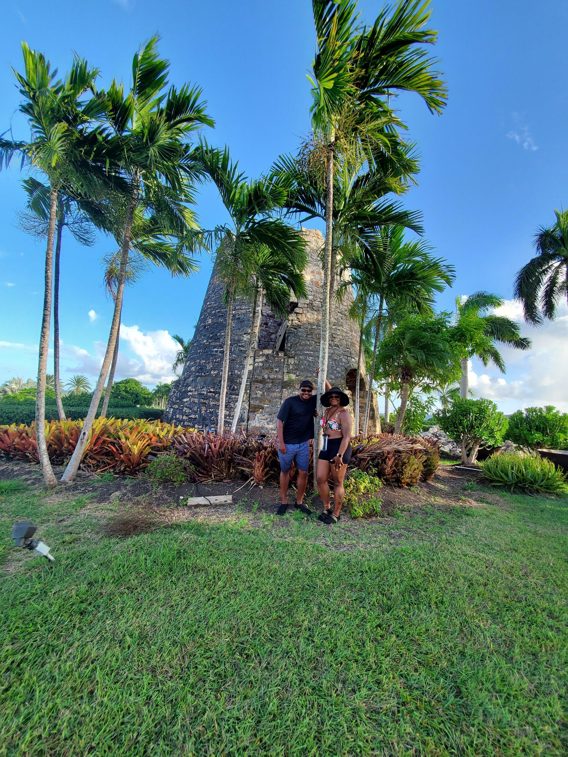 A man and a woman are standing in front of a pyramid in a park.
