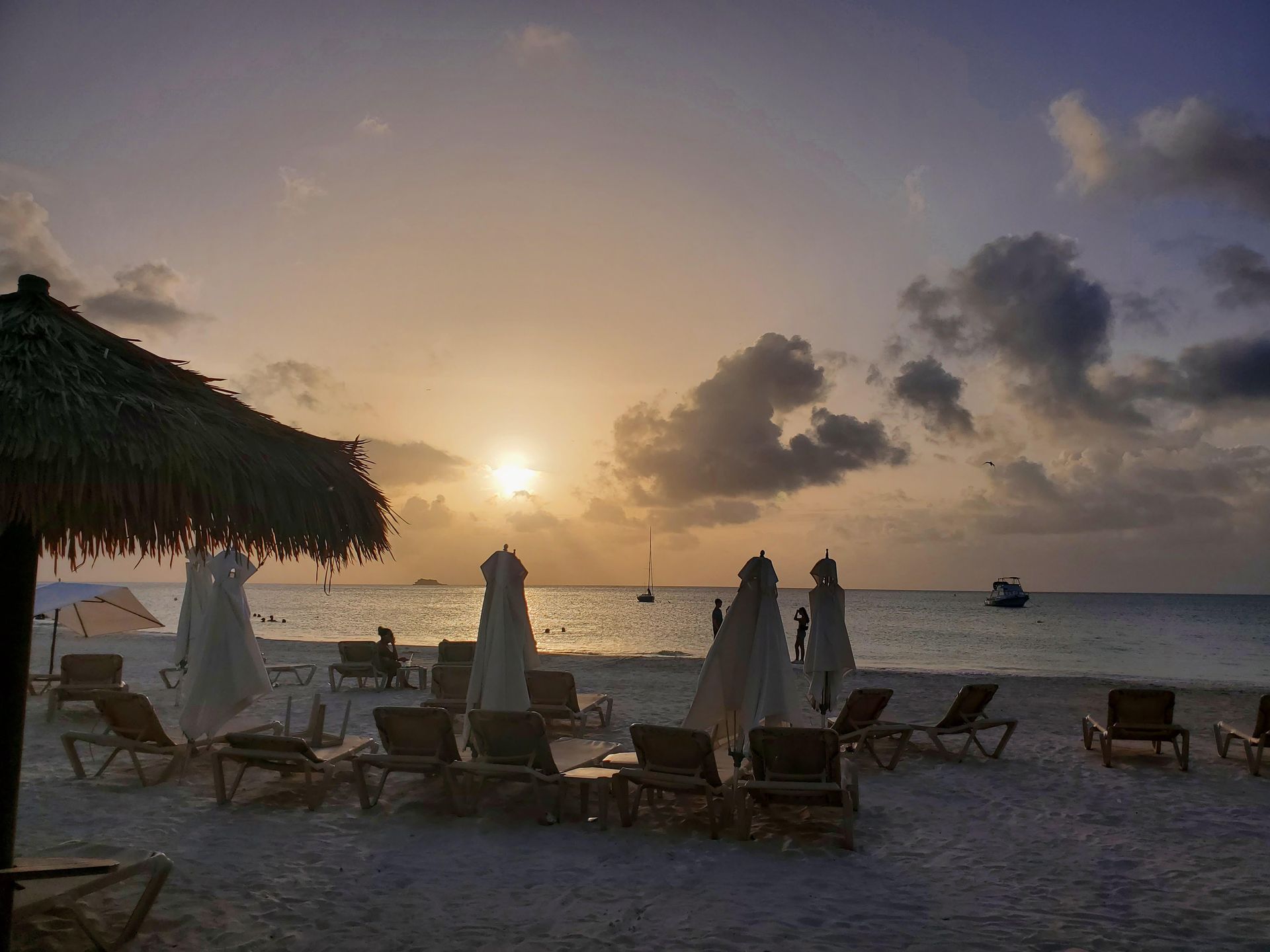 A beach with chairs and umbrellas at sunset