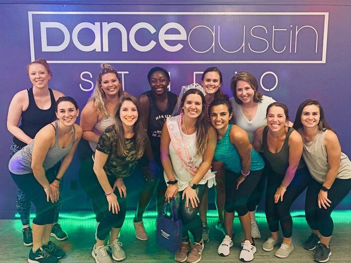 A group of women are posing for a picture in front of a dance studio.