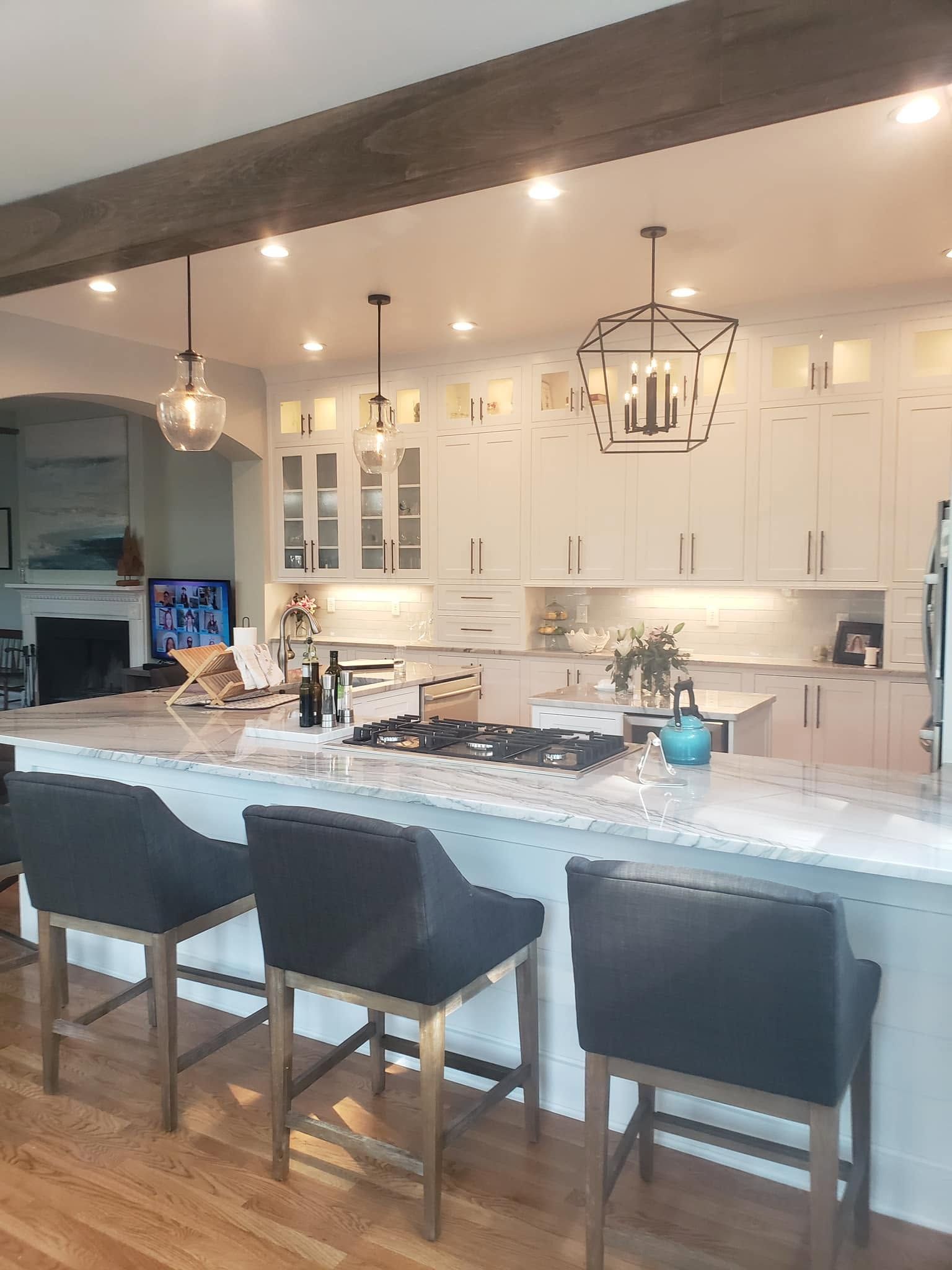 Bright modern kitchen with island seating, white cabinets, pendant lights, and stone countertops