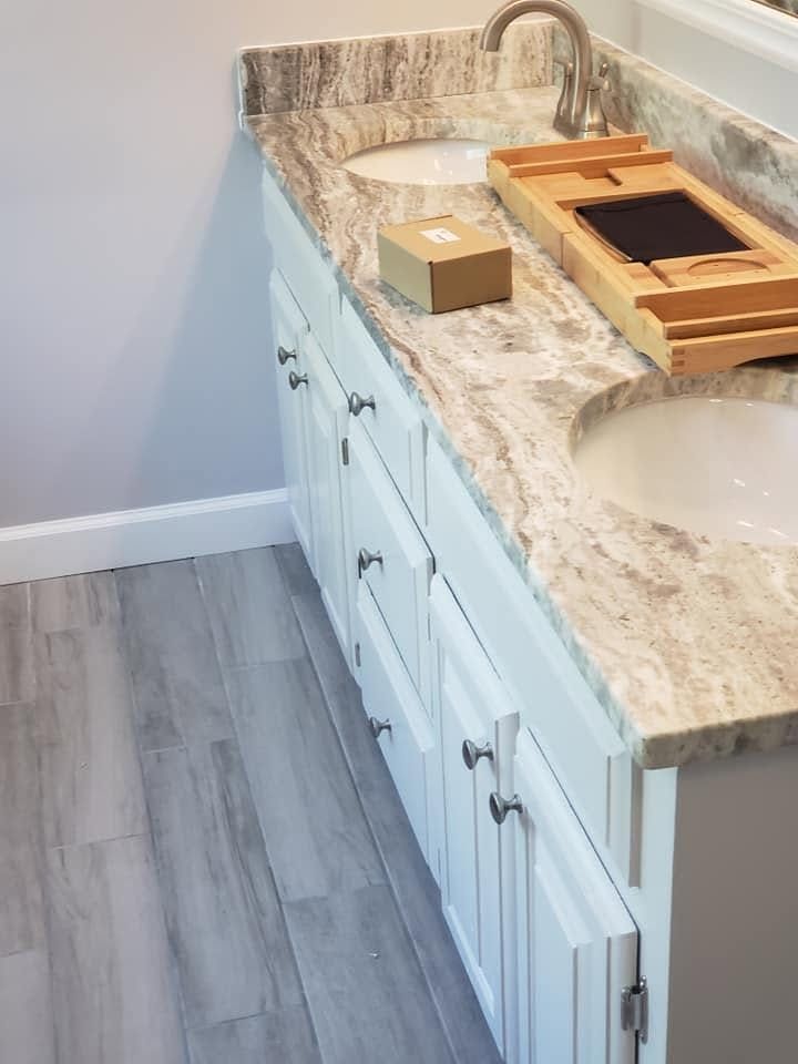 Bathroom vanity with marble countertop, sink, faucet, and wooden tray holding a small box.