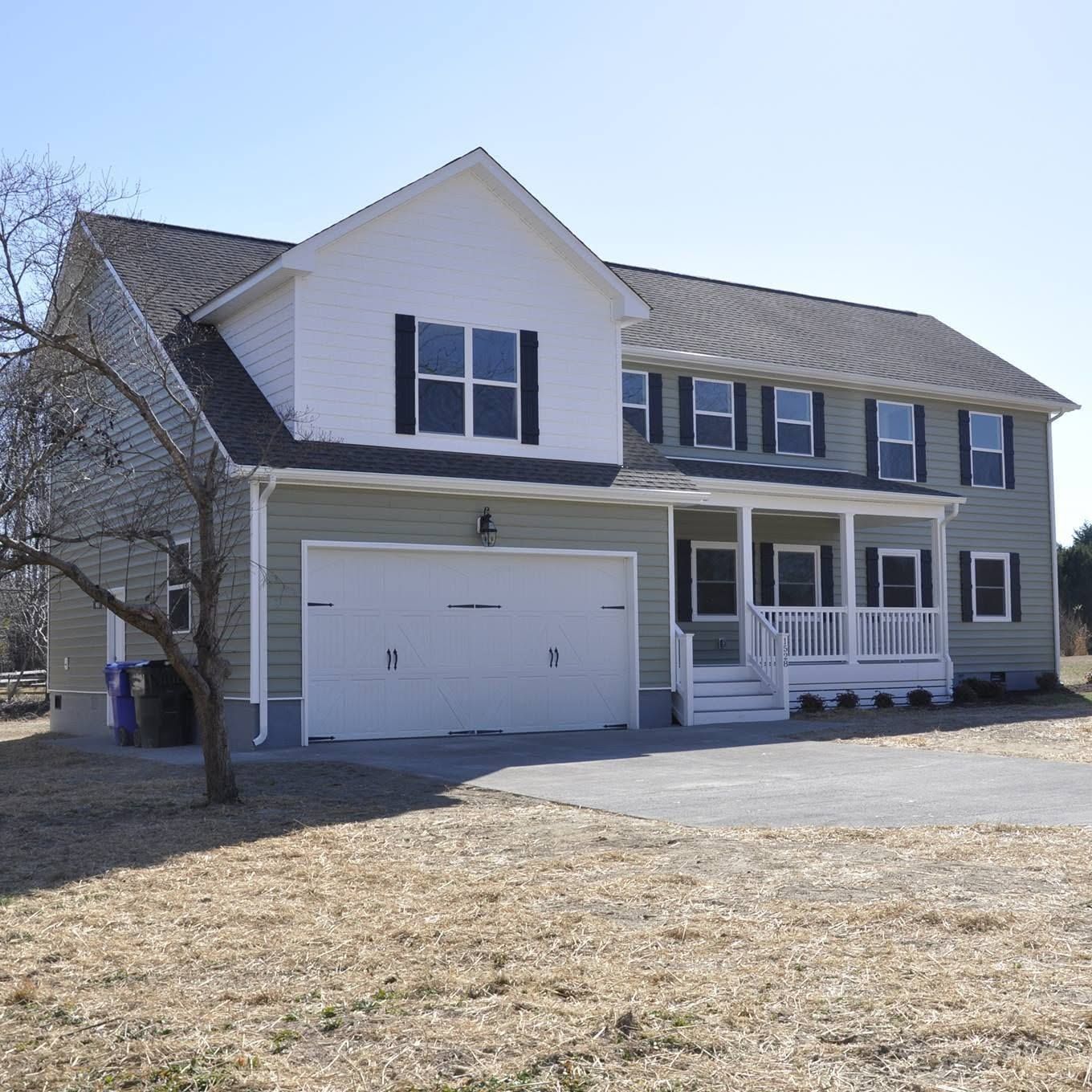 Two-story suburban house with white trim, gray siding, and a double garage on a sunny day