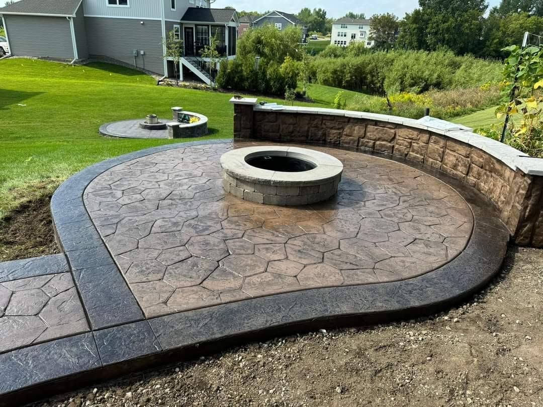 Backyard stone patio with a circular fire pit and curved retaining wall