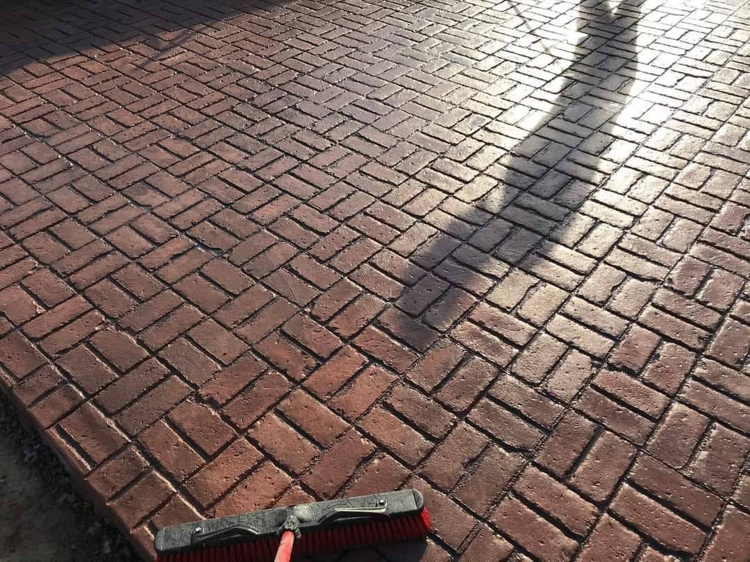 Brick-paved sidewalk with a person’s shadow and a small object at the bottom edge