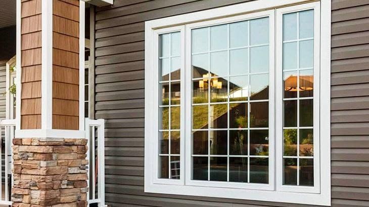Front exterior of a house with a large white-framed window and stone and siding facade