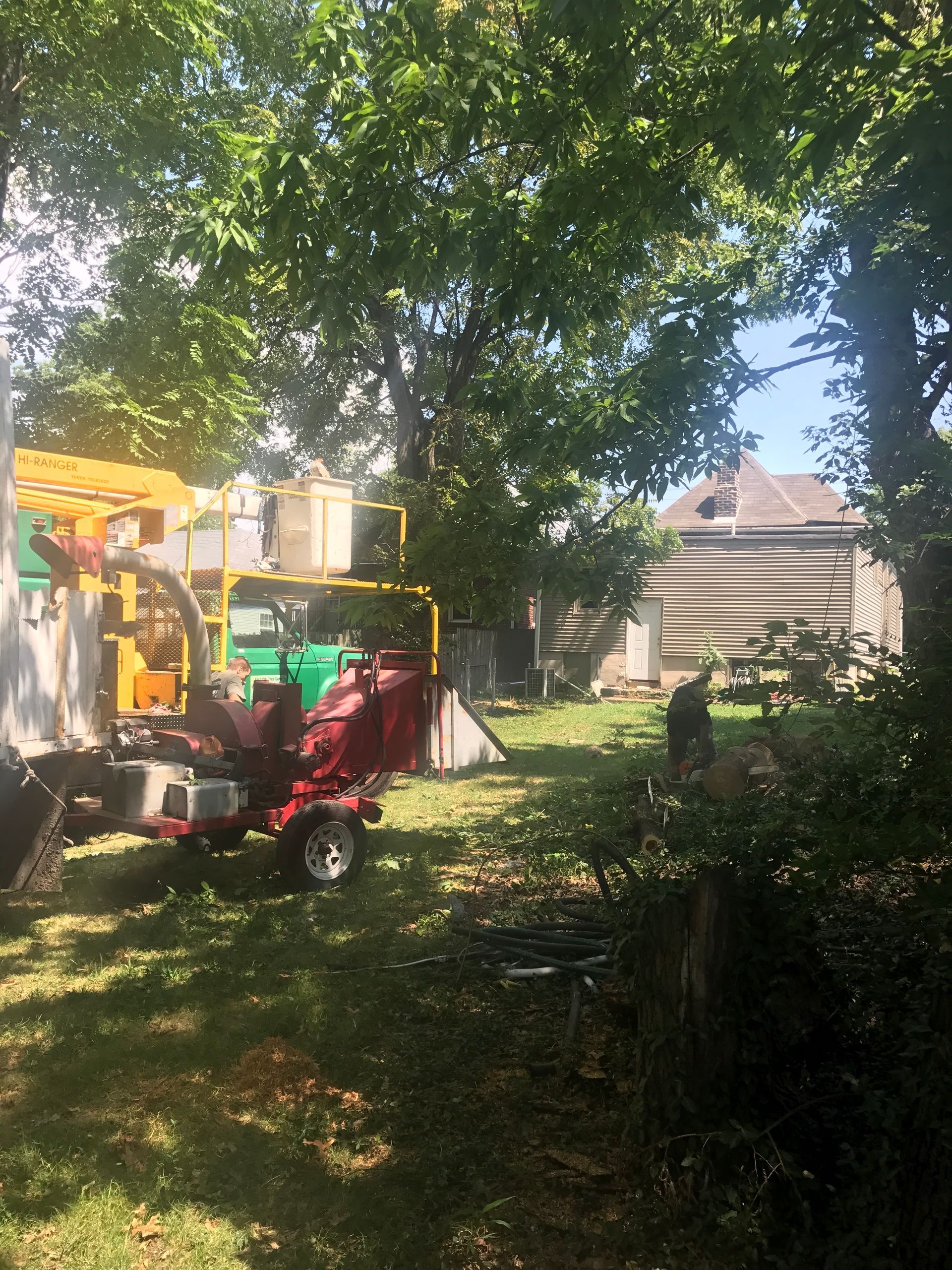 Backyard playground with red toy ride-on, colorful playset, trees, and a house in the background