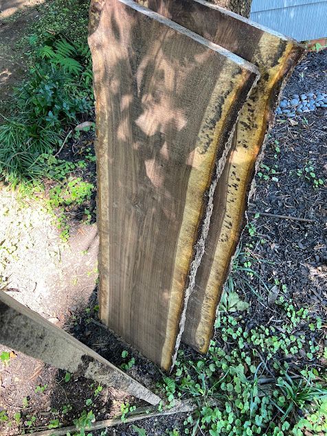 Close-up of a weathered wooden post with peeling paint beside a dirt path and green groundcover.