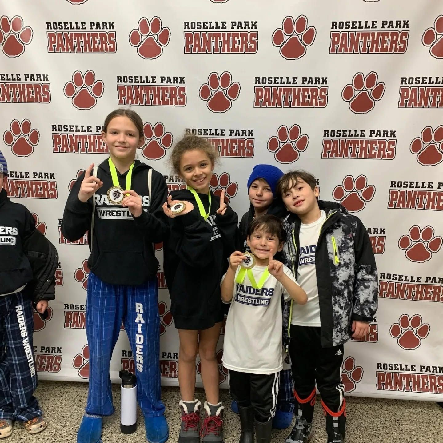 Children posing on a podium with medals at a Roselle Park Panthers event backdrop.