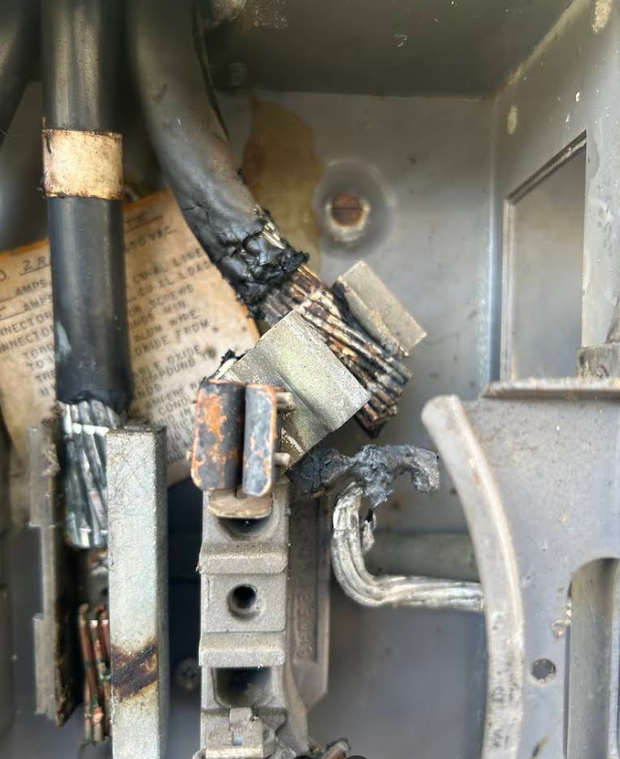Burned electrical wiring and metal components inside a panel box
