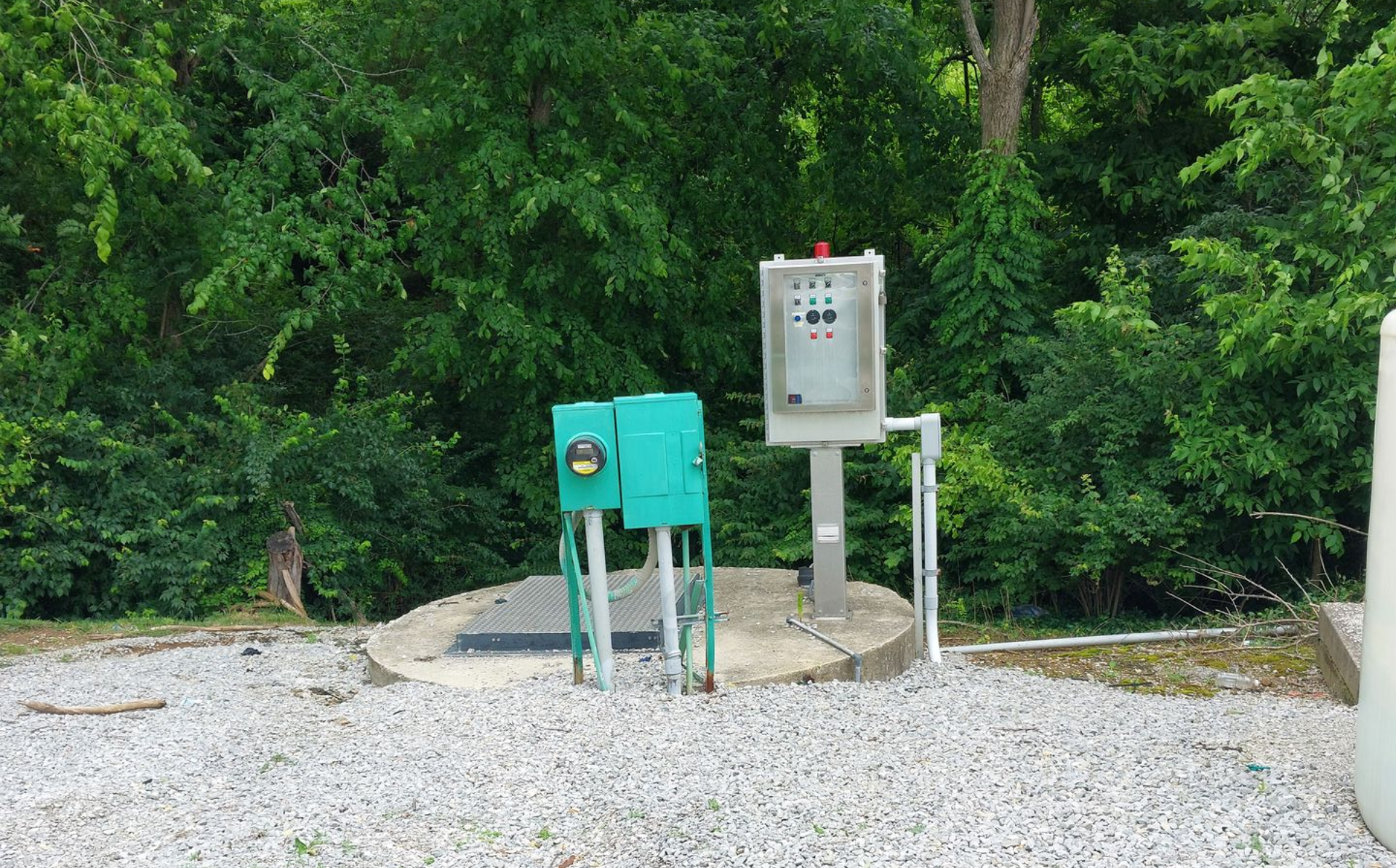 Green industrial pump with three motors on a workbench, including gray, blue, and red units.
