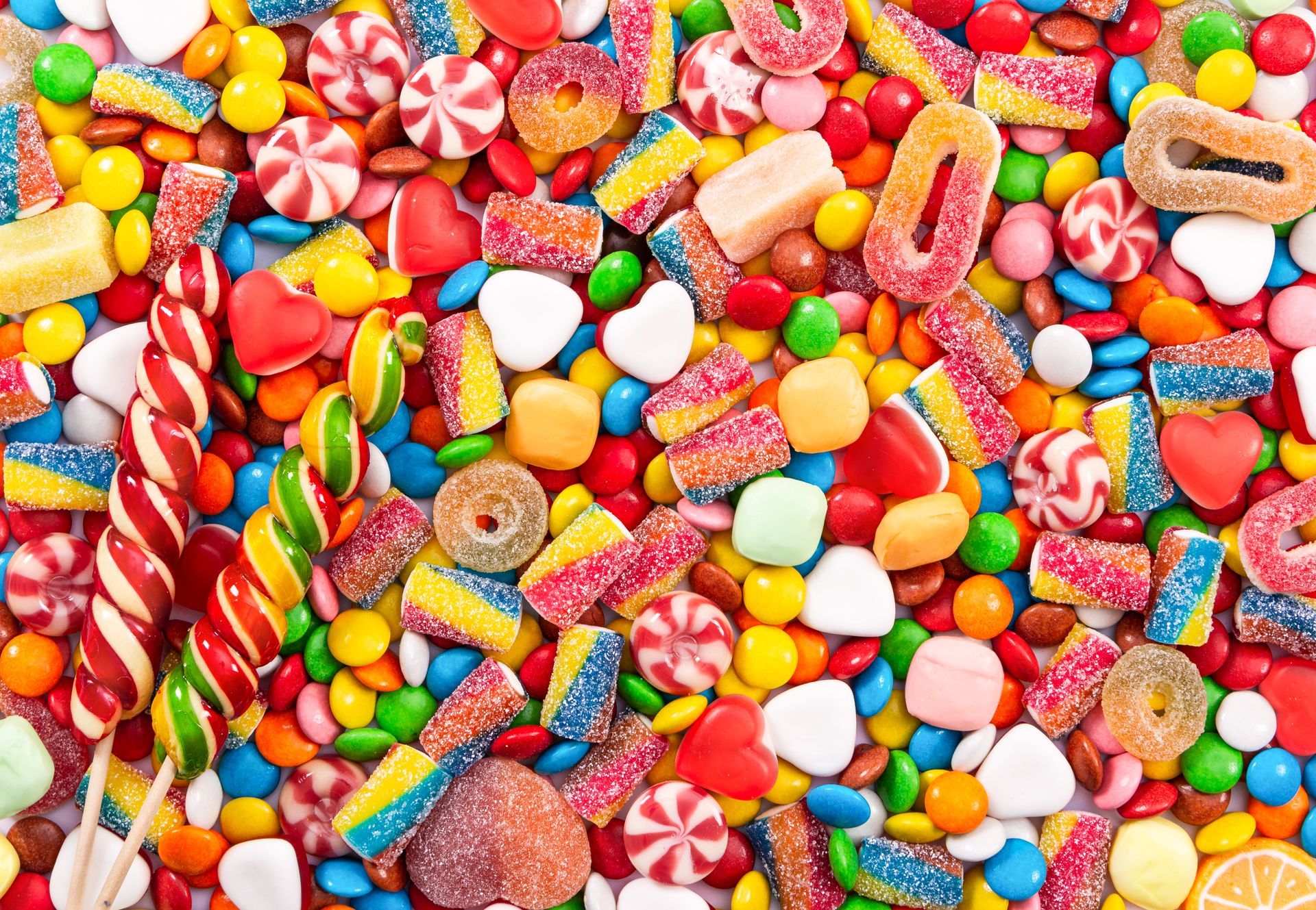 Surtido de dulces de colores: piruletas, anillos de gelatina, caramelos duros y chocolates.
