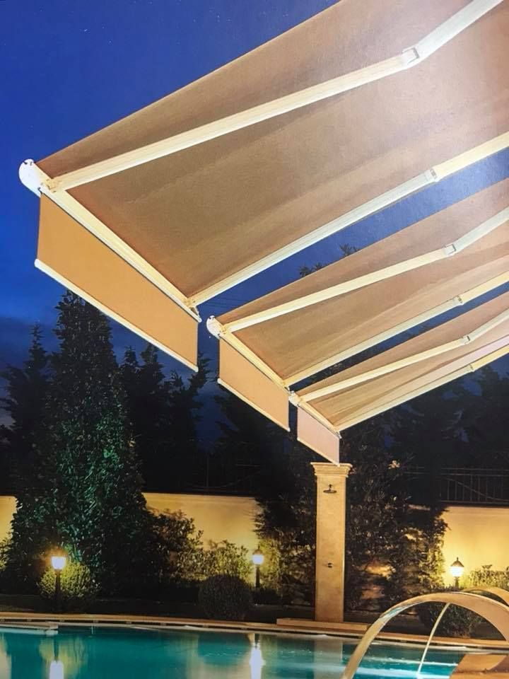 Tende da sole retrattili marroni sopra una piscina di notte.
