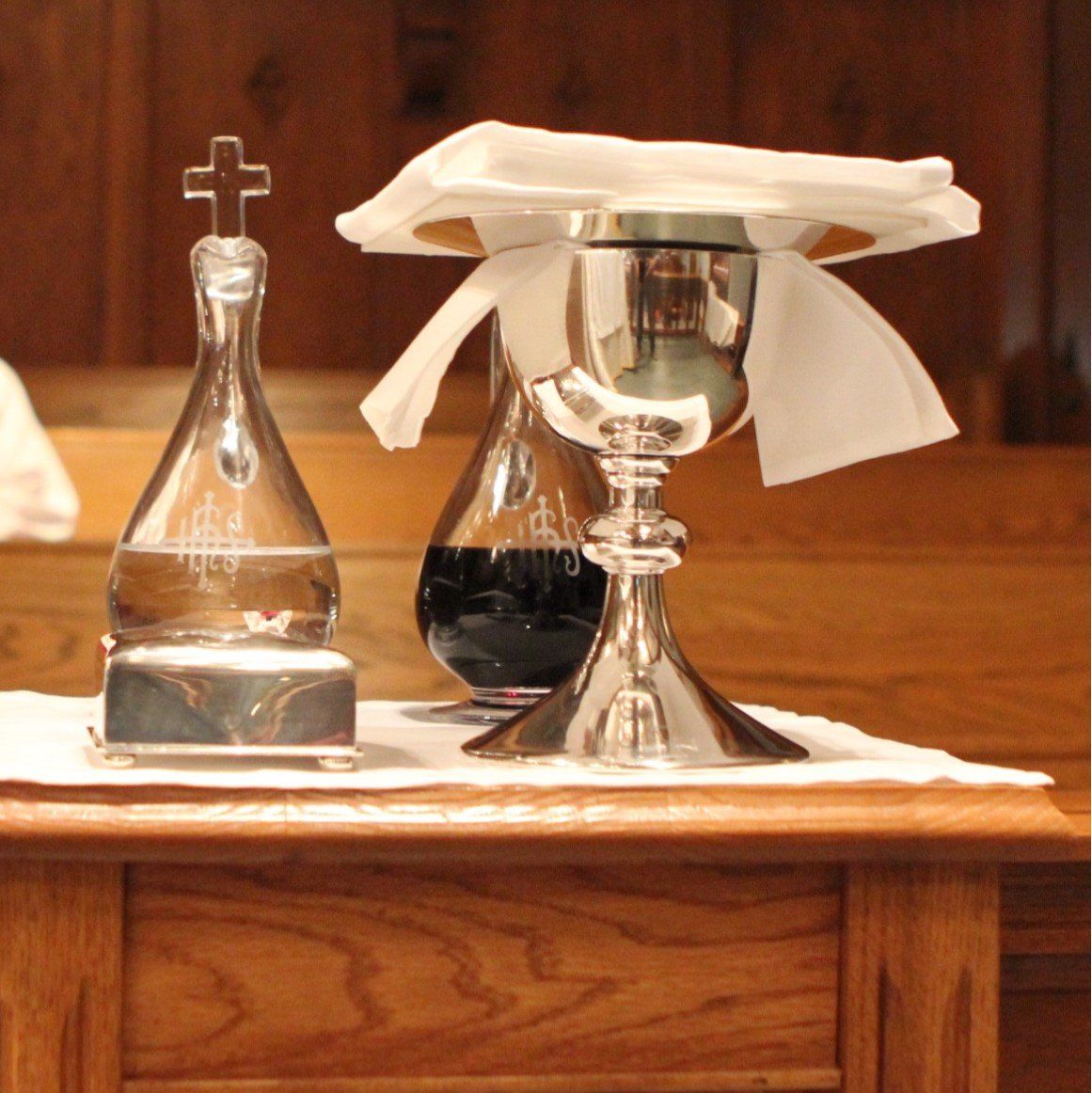 A bottle with a cross on it sits next to a chalice